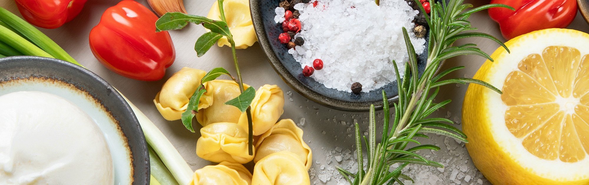 Frische Zutaten wie Paprika, Zitrone, Kräuter, Knoblauch auf einem Tisch