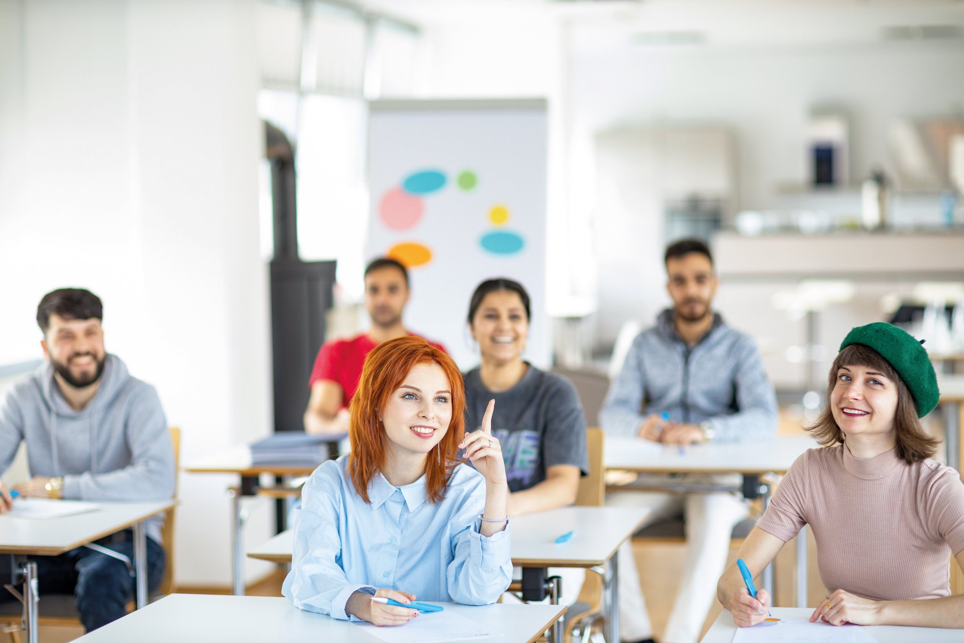 Erwachsene unterschiedlicher Herkunft sitzen in einem Klassenraum zum Deutschsprachkurs