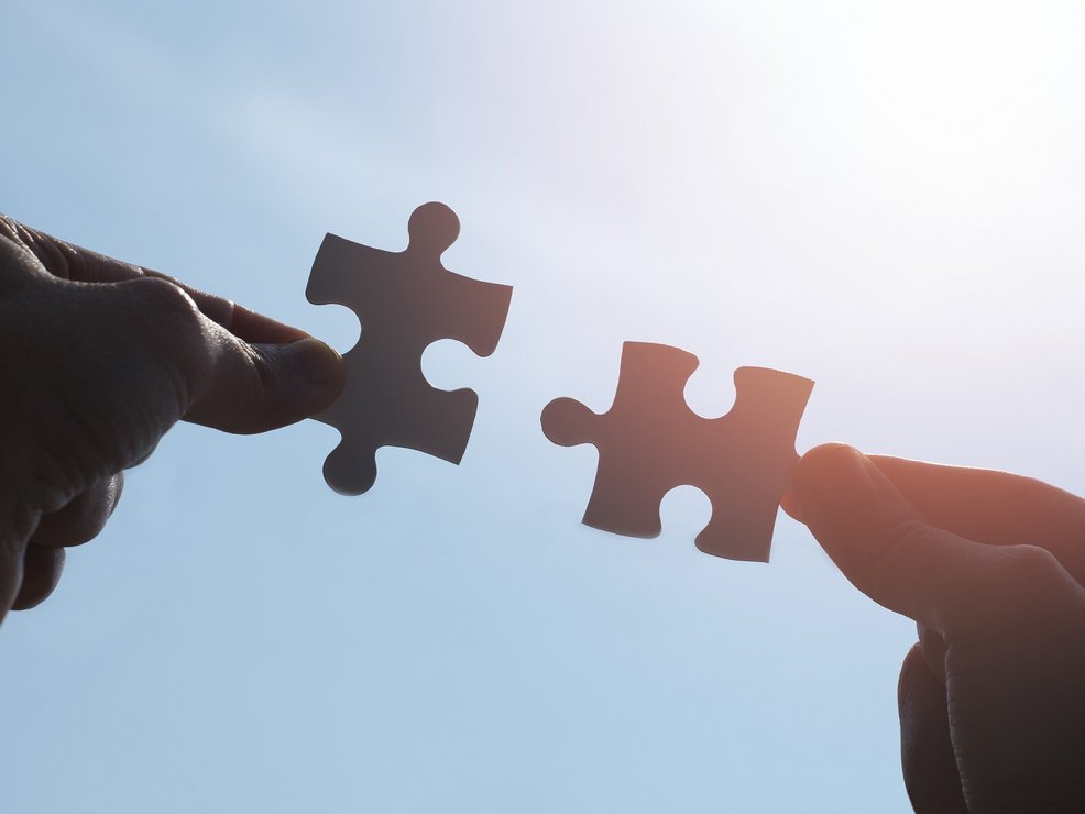 Zwei Puzzleteile die zusammengeführt werden