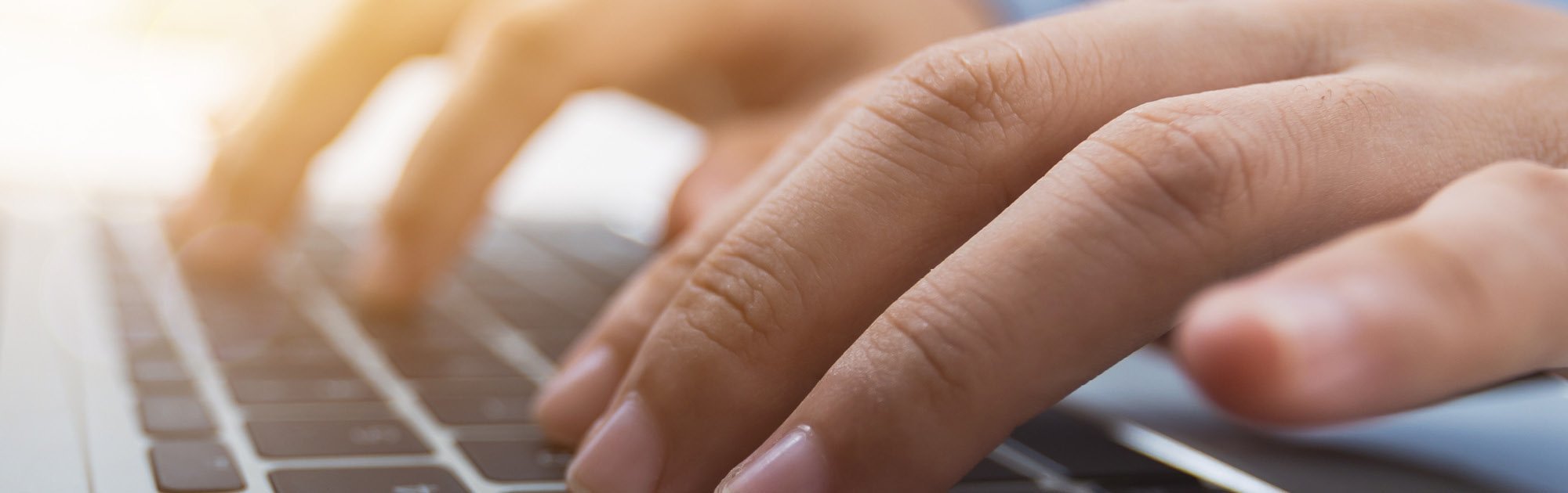 Hände tippen auf einer Laptoptastatur