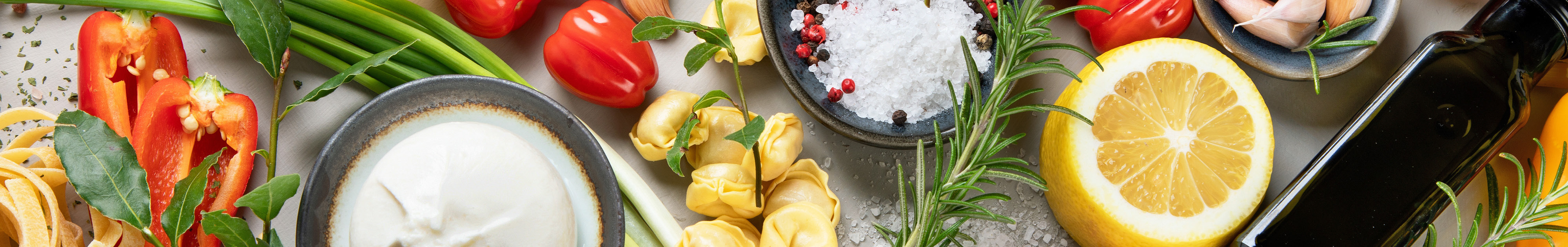 Frische Zutaten wie Paprika, Zitrone, Kräuter, Knoblauch auf einem Tisch